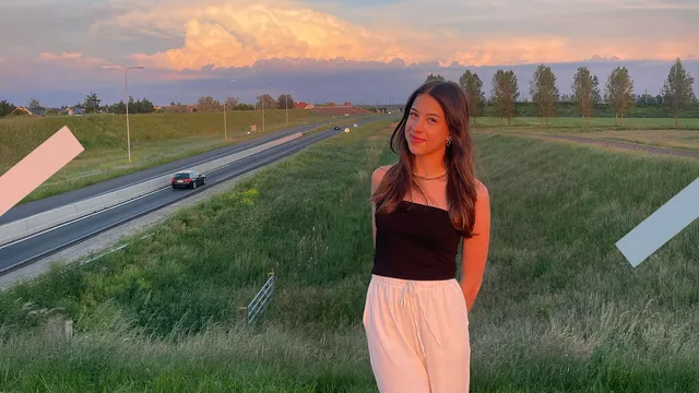 Je ziet een weiland waarlangs een weg loopt. In het weiland staat een wit meisje, dit is Anna.