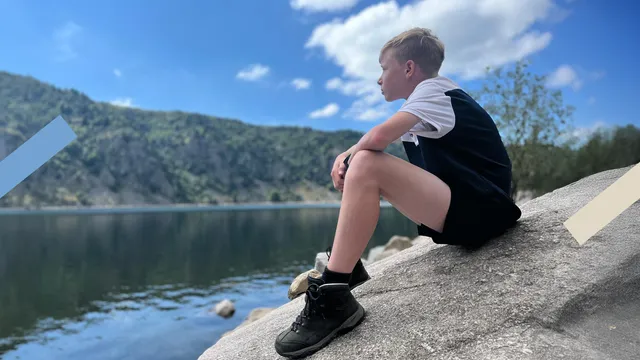 Je ziet een jongen zitten op een rots terwijl hij in de verte staart. Dit is Corné, de jongen die in dit artikel vertelt over zijn geloof.