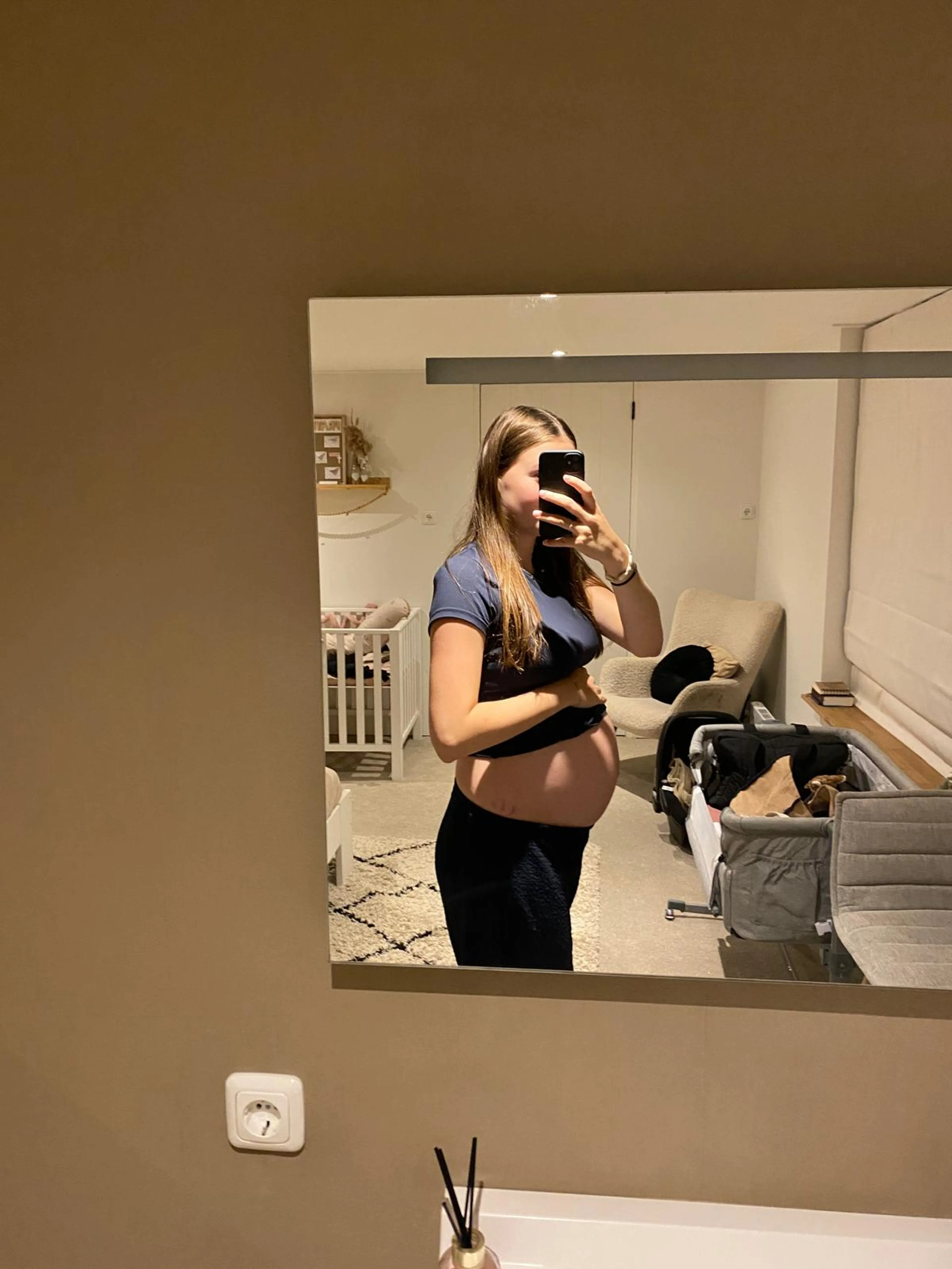 Charissa die in de spiegel een foto maakt van haarzelf met een zwangere buik.