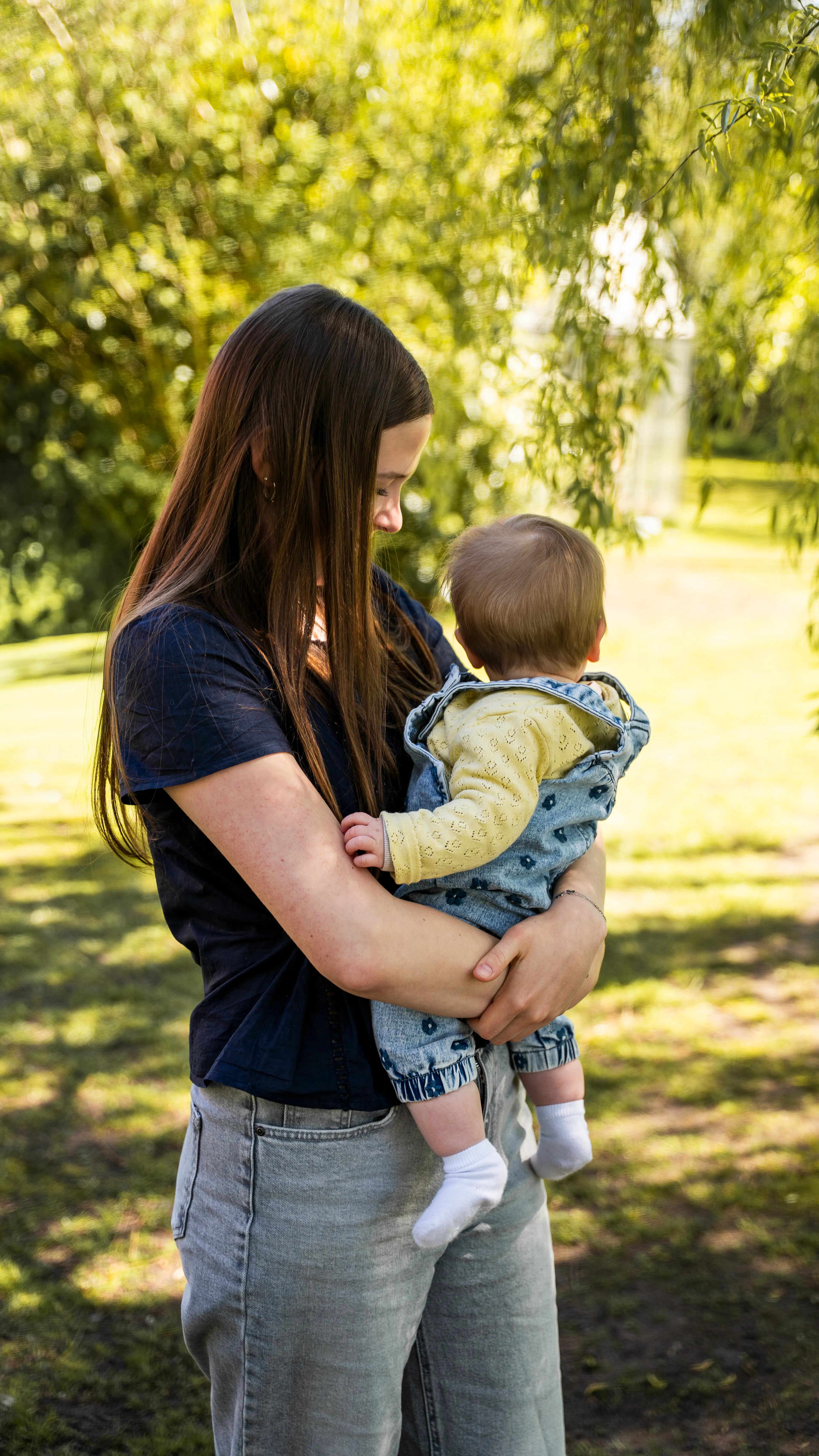 Charissa met haar baby vast in de tuin, de baby kijkt niet de camera in.