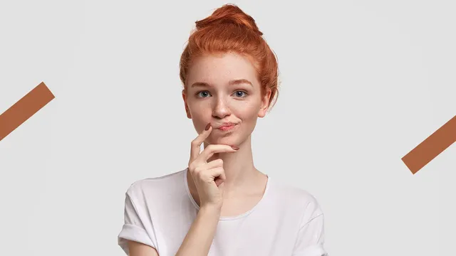 Op de foto zie je een meisje met een wit shirt aan en rood haar. Ze leunt met haar gezicht op haar hand en kijkt vertwijfeld in de camera.