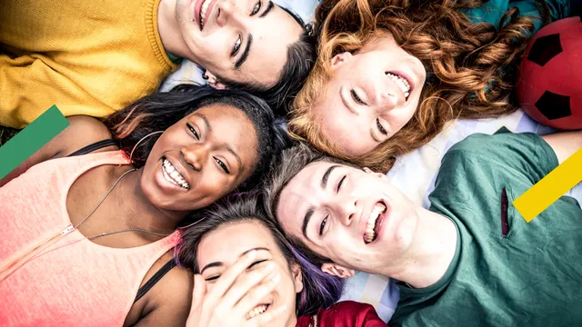 Jongeren liggen op de grond in een cirkel en hebben een leuke tijd.