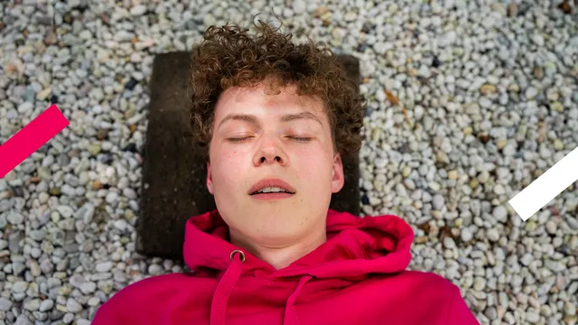 Je ziet redacteur Jelte met een roze BEAM-trui aan slapen met z'n hoofd op een stoeptegel. Hij kijkt vredig.