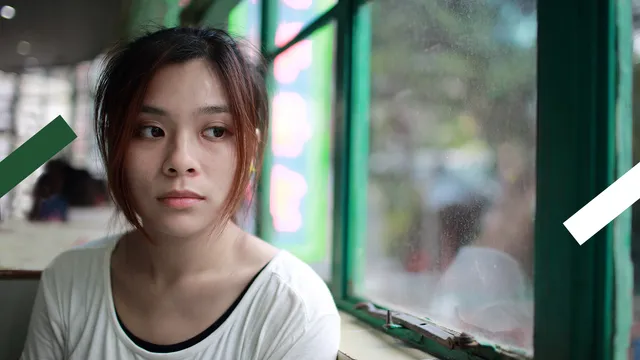 Een jong meisje dat verdrietig en verslagen uit een raam staart.