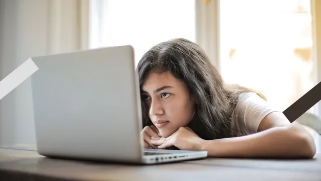 Meisje kijkt verveelt naar laptopscherm.