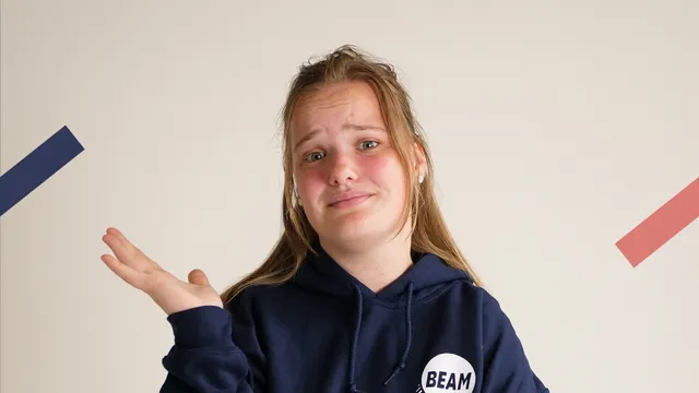 Blond meisje met donkerblauwe trui die vragend kijkt.