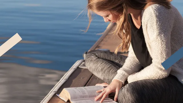 Meisje die een bijbel leest op een pier.