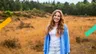 Meisje genaamd Hanna staat op de heide en kijkt lachend naar de camera.